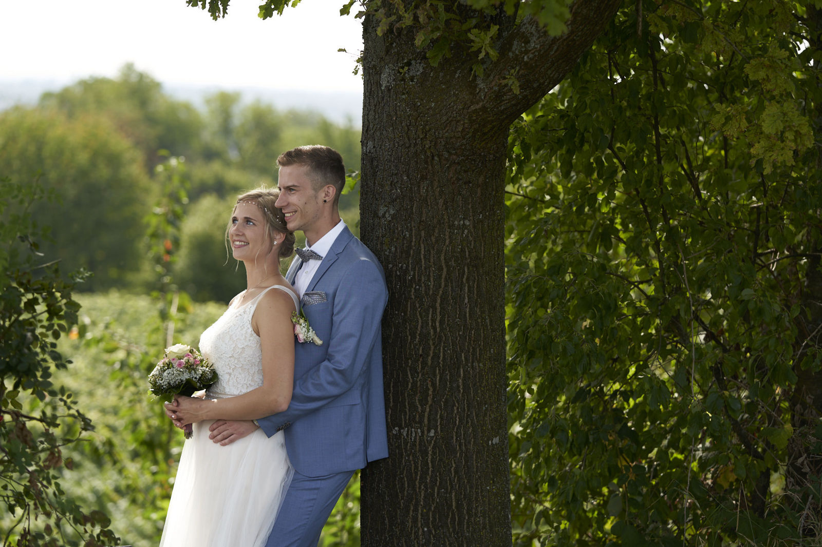 Diese Paar lehnt sich entspannt an einem Baum an und schaut einfach nur in die Ferne - ganz entspannt. Als Hochzeitsfotograf in Freiburg finde ich immer die schönsten Plätze