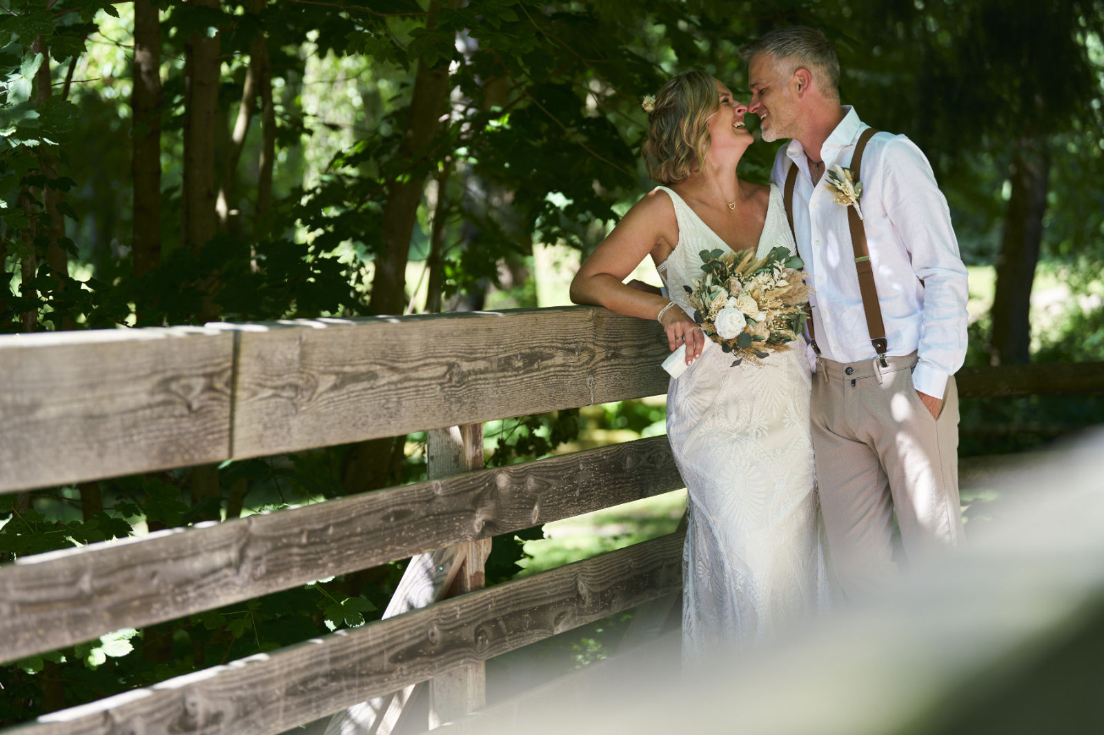 Dieses Brautpaar steht auf einer rustikalen Holzbrücke mitten im Grünen - und meine Aufgabe als Hochzeitsfotograf ist es diese Momente auch zu inszenieren, ohne das sie gestellt aussehen, denn ihr sollte euch wohl fühlen