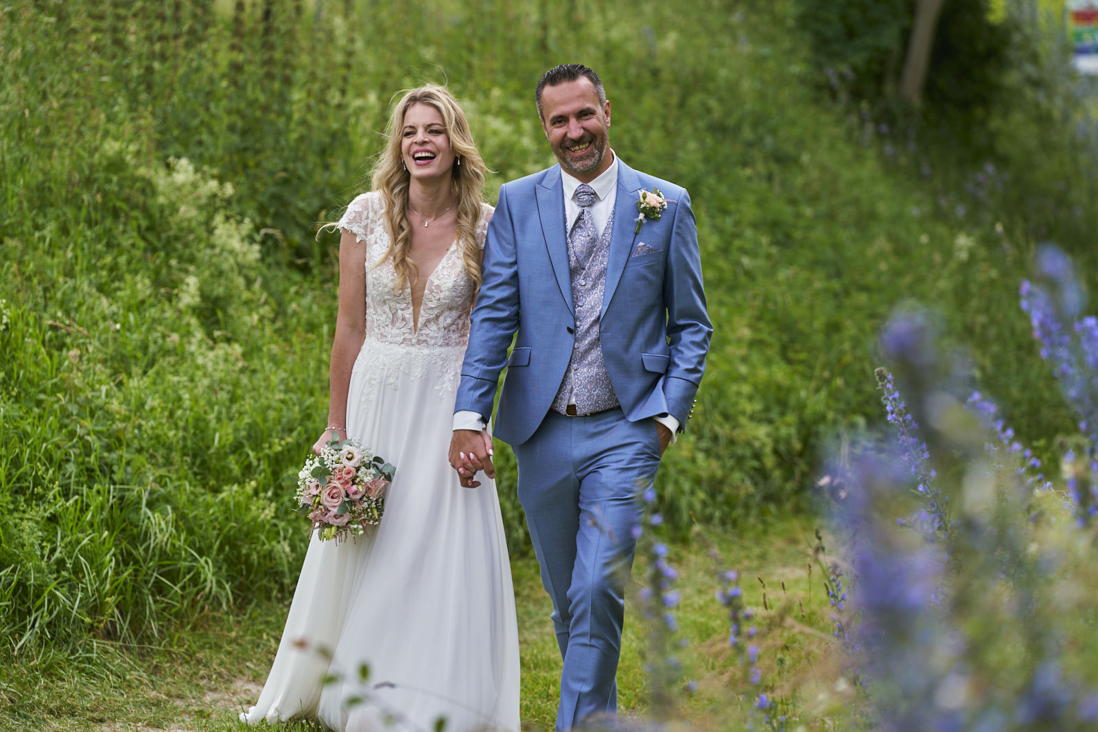 Das Brautpaar läuft entspannt über eine Wiese und hat einfach nur Spaß. Diese Momente schaffe ich als Hochzeitsfotograf in Freiburg
