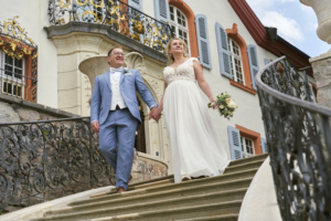 Brautpaar läuft Treppe herunter auf Schloss Bürgeln und der Hochzeitsfotograf wartet